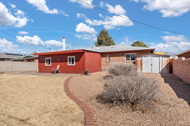 back of property featuring an outbuilding, a shed, a patio, and a fenced backyard