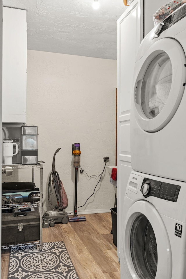 washroom with cabinet space, light wood-type flooring, and stacked washing maching and dryer