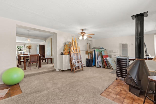 interior space featuring a textured ceiling, a wood stove, and a ceiling fan