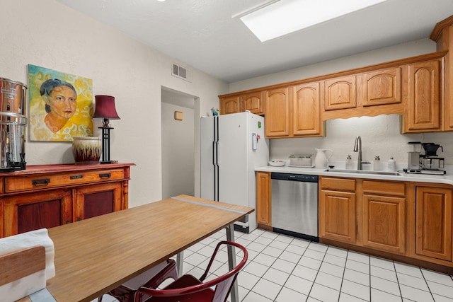 kitchen featuring visible vents, dishwasher, light countertops, freestanding refrigerator, and a sink