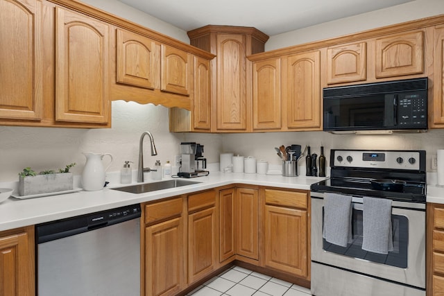 kitchen with a sink, appliances with stainless steel finishes, light countertops, and light tile patterned floors