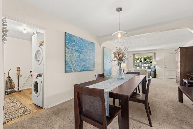 dining area featuring light carpet and stacked washing maching and dryer