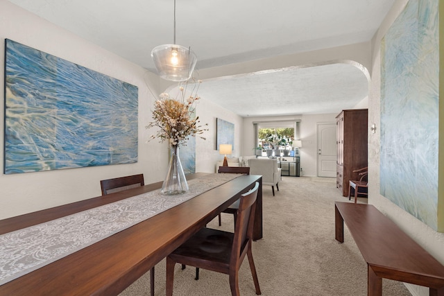 dining space featuring arched walkways and carpet floors