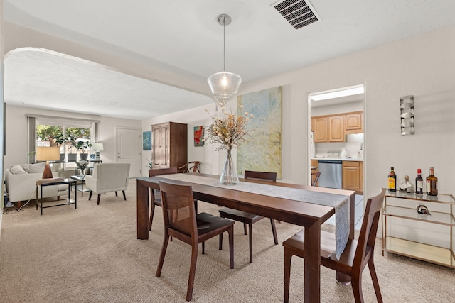 dining space featuring arched walkways, visible vents, and light colored carpet