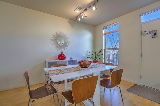 dining space featuring light wood-type flooring, visible vents, baseboards, and rail lighting