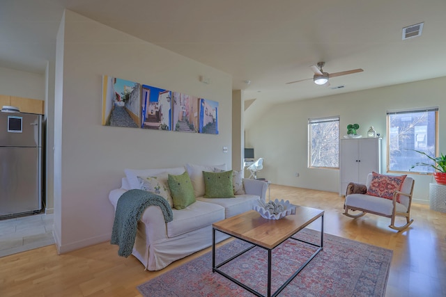 living room with baseboards, visible vents, a ceiling fan, and light wood-style floors