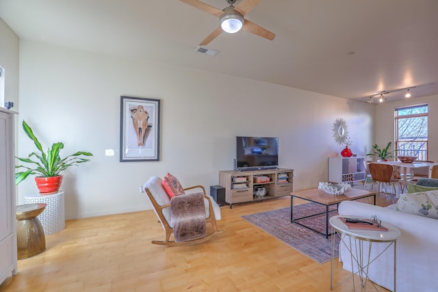 living area with ceiling fan, visible vents, baseboards, and wood finished floors