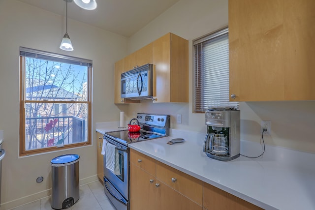 kitchen featuring pendant lighting, stainless steel appliances, light countertops, light tile patterned floors, and baseboards