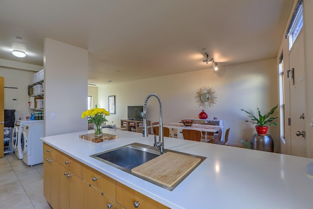 kitchen with light tile patterned floors, separate washer and dryer, a sink, and light countertops