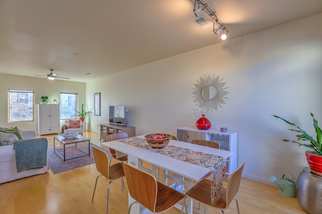 dining room with visible vents, light wood-style floors, rail lighting, baseboards, and ceiling fan