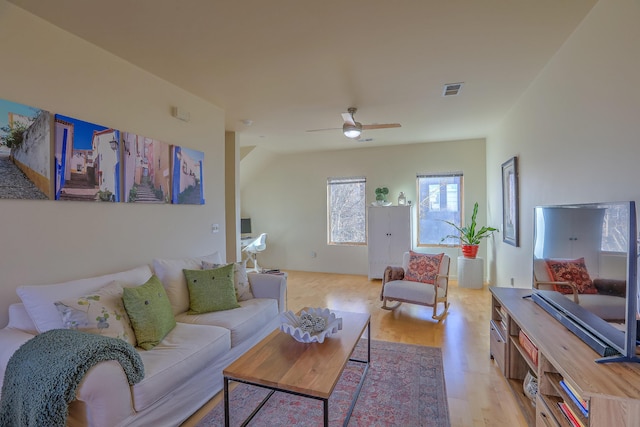 living room featuring a ceiling fan, visible vents, and light wood-type flooring