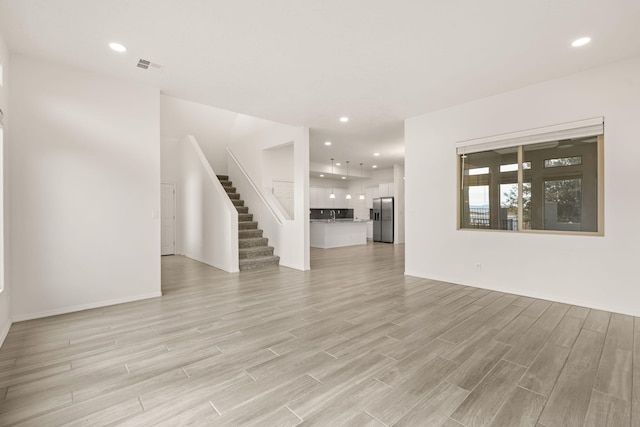 unfurnished living room featuring light wood-style floors, visible vents, and recessed lighting