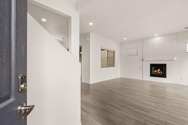 unfurnished living room with a glass covered fireplace, wood finished floors, and recessed lighting