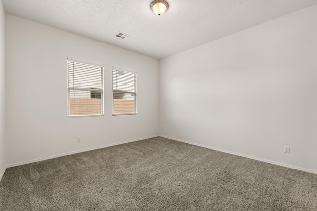 carpeted spare room with baseboards, a textured ceiling, and visible vents