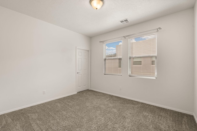 empty room featuring a textured ceiling, carpet flooring, baseboards, and visible vents