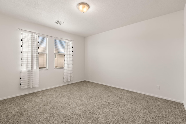 unfurnished room featuring carpet floors, a textured ceiling, baseboards, and visible vents