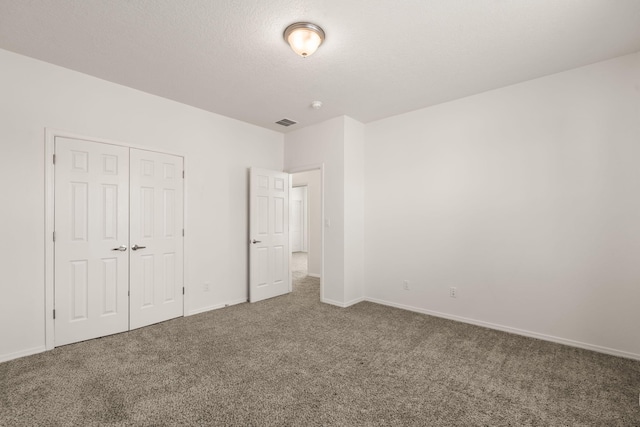 unfurnished bedroom with visible vents, carpet floors, a closet, baseboards, and a textured ceiling