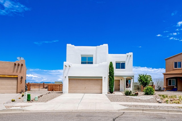 adobe home with concrete driveway, an attached garage, fence, and stucco siding