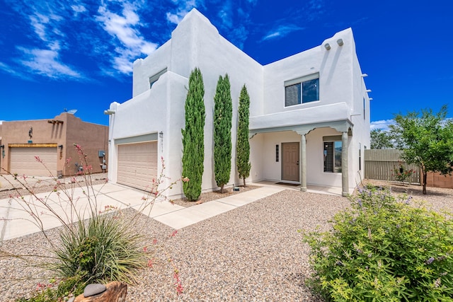 southwest-style home with stucco siding, concrete driveway, a garage, and fence