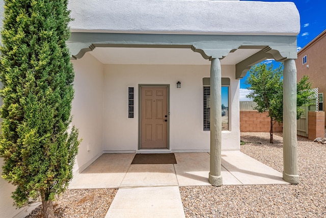 doorway to property featuring stucco siding and fence