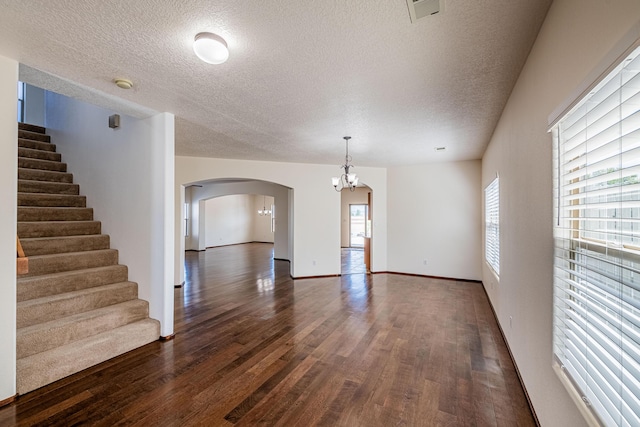 interior space featuring an inviting chandelier, dark wood-type flooring, visible vents, and arched walkways