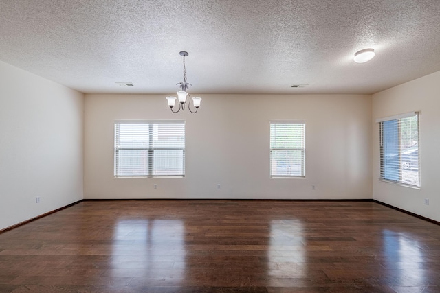 empty room featuring a notable chandelier, wood finished floors, and baseboards