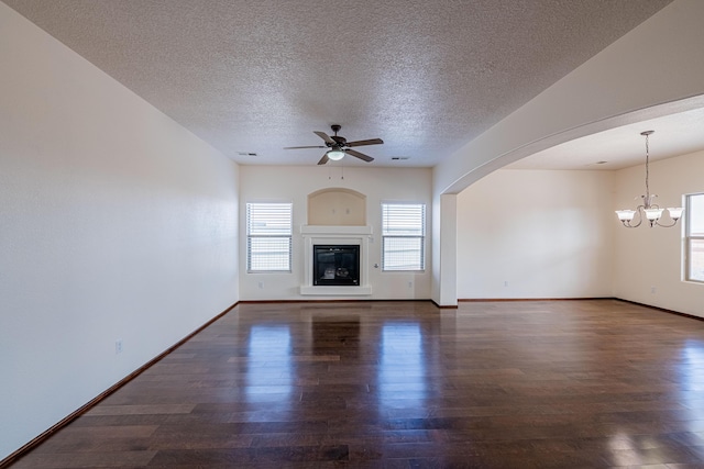 unfurnished living room with a glass covered fireplace, ceiling fan with notable chandelier, visible vents, and wood finished floors