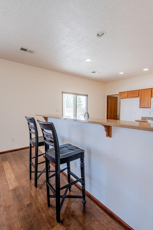 dining space featuring a textured ceiling, dark wood-style floors, visible vents, and baseboards