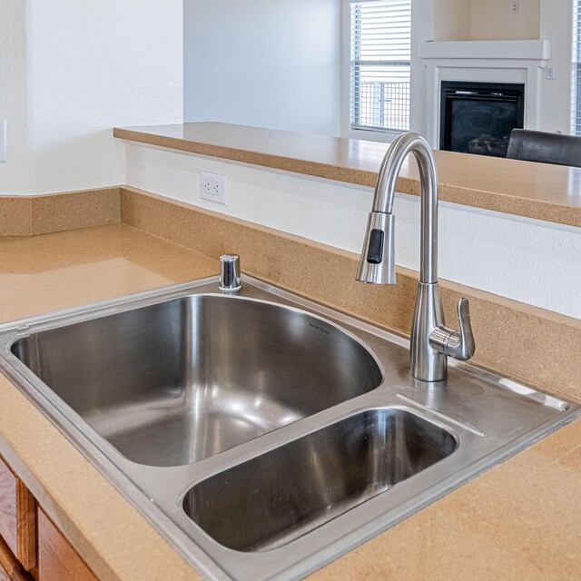 interior details with a sink, a glass covered fireplace, and light countertops