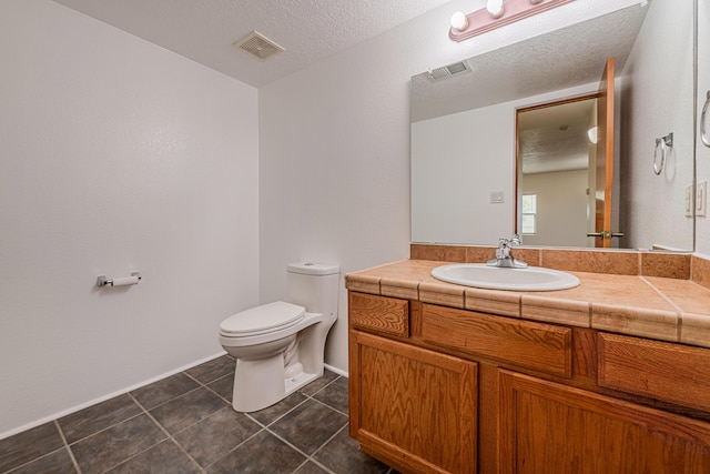 bathroom featuring vanity, toilet, visible vents, and a textured ceiling