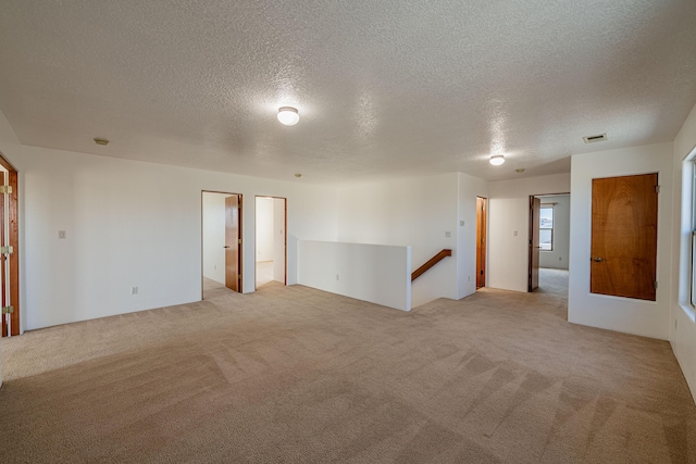 carpeted empty room with visible vents and a textured ceiling