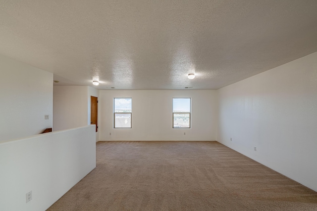 unfurnished room featuring light colored carpet and a textured ceiling