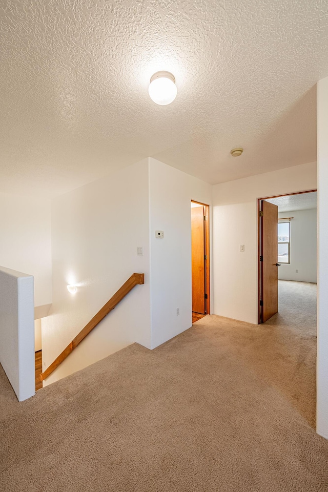 carpeted empty room with a textured ceiling