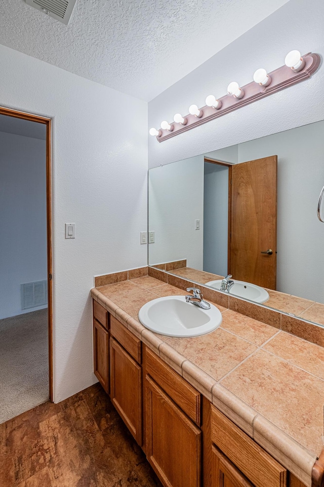 bathroom with vanity, visible vents, and a textured ceiling