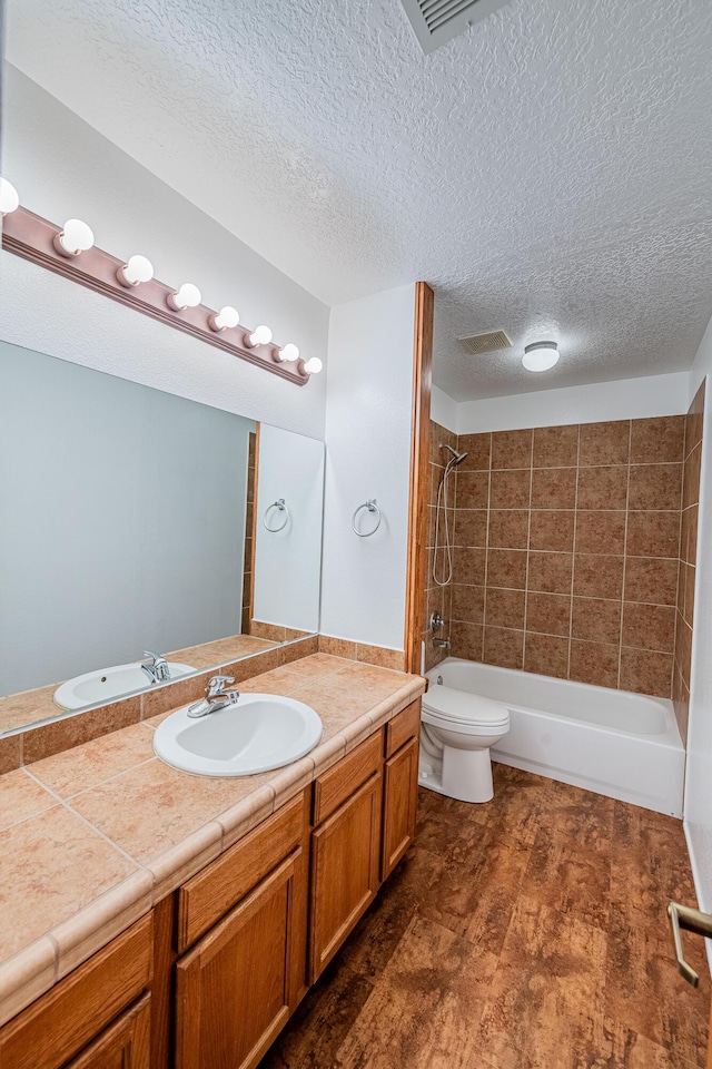 bathroom with vanity, visible vents,  shower combination, a textured ceiling, and toilet