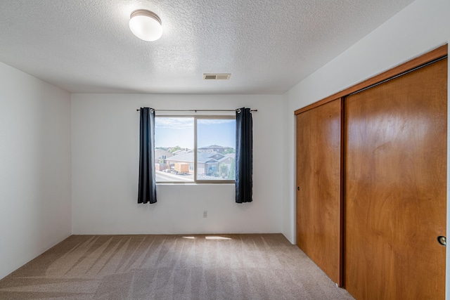 unfurnished bedroom featuring a closet, visible vents, carpet floors, and a textured ceiling