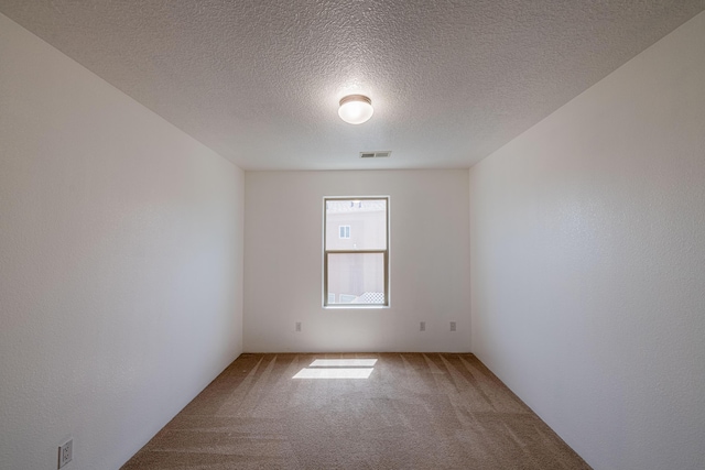 unfurnished room featuring light carpet, visible vents, a textured ceiling, and a textured wall