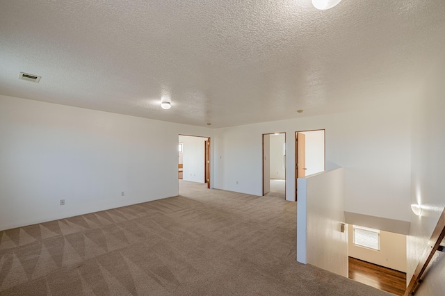 carpeted empty room featuring visible vents and a textured ceiling