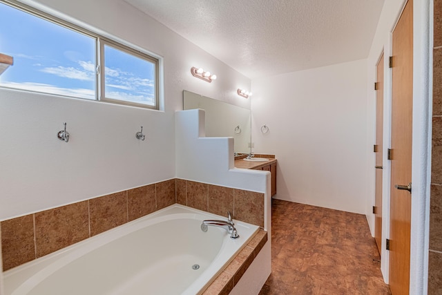 full bathroom with a textured ceiling, vanity, and a garden tub