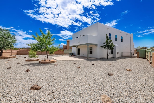 rear view of house with a fenced backyard, stucco siding, a patio, and a gate