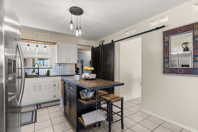 kitchen featuring butcher block countertops, a sink, white cabinetry, light tile patterned flooring, and stainless steel fridge with ice dispenser