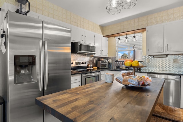 kitchen with a kitchen island, backsplash, stainless steel appliances, butcher block counters, and wallpapered walls