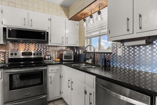 kitchen featuring a sink, decorative backsplash, appliances with stainless steel finishes, and white cabinetry