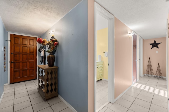 hall with light tile patterned floors, baseboards, and a textured ceiling