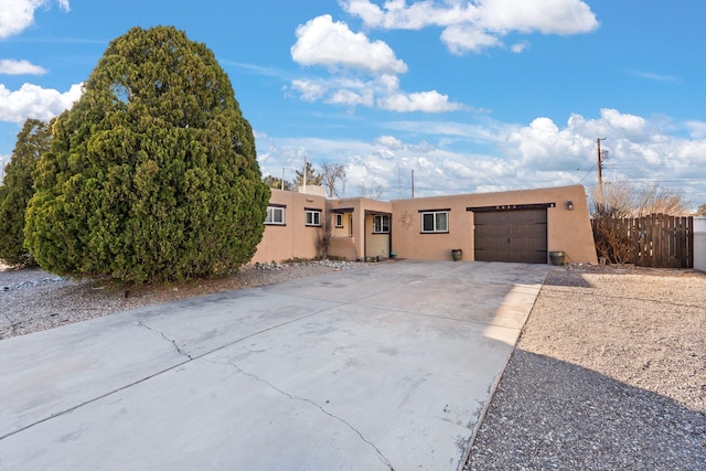 pueblo-style home featuring a garage, driveway, and stucco siding