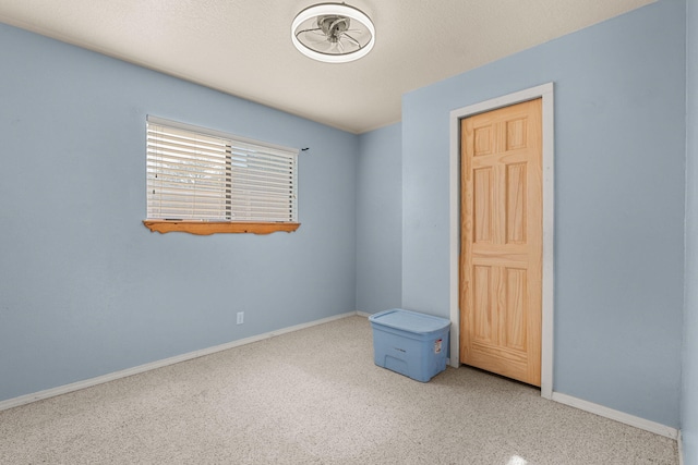 spare room featuring baseboards, a textured ceiling, and carpet flooring