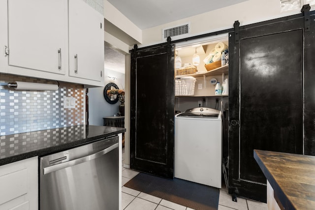 kitchen featuring visible vents, dishwasher, a barn door, light tile patterned floors, and washer / dryer