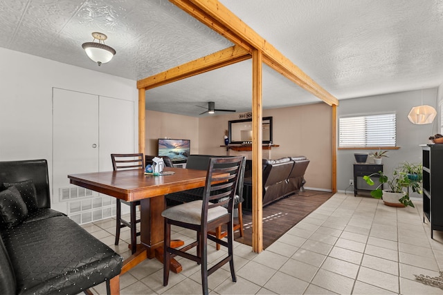 dining area featuring beamed ceiling, a textured ceiling, light tile patterned floors, baseboards, and ceiling fan