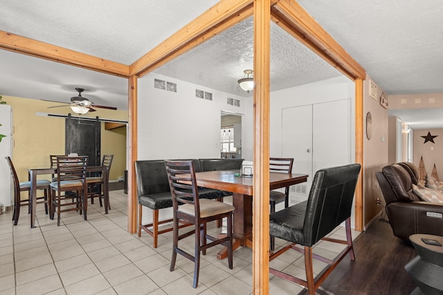 tiled dining area with beamed ceiling, a textured ceiling, visible vents, and ceiling fan