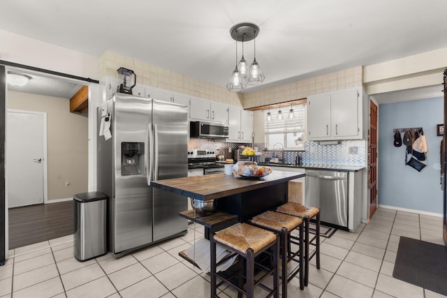 kitchen with light tile patterned floors, decorative backsplash, appliances with stainless steel finishes, and a sink